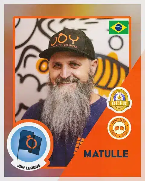 Paulo Matulle sorrindo na fábrica Joy Project Brewing, usando boné preto com logo da Joy